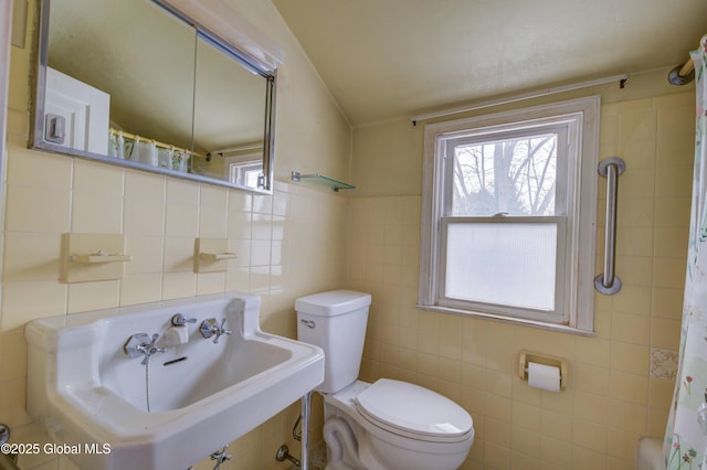 bathroom featuring tile walls, toilet, a healthy amount of sunlight, and a sink