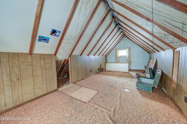 additional living space featuring vaulted ceiling and wooden walls