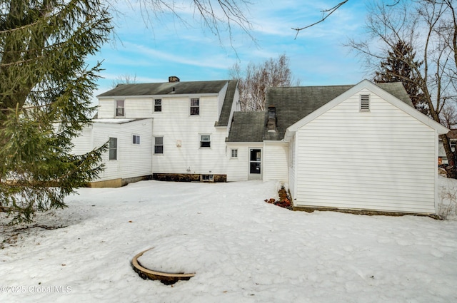 snow covered property with roof with shingles and a chimney