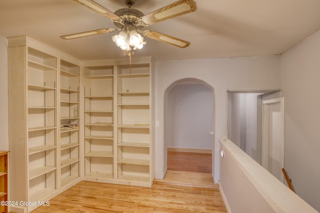 interior space with a ceiling fan, arched walkways, and wood finished floors