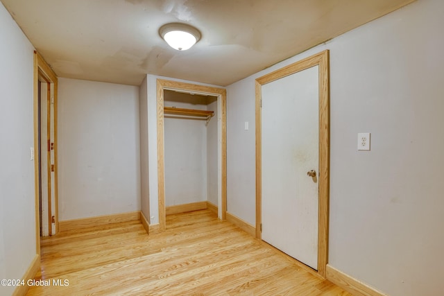 unfurnished bedroom featuring a closet, baseboards, and wood finished floors