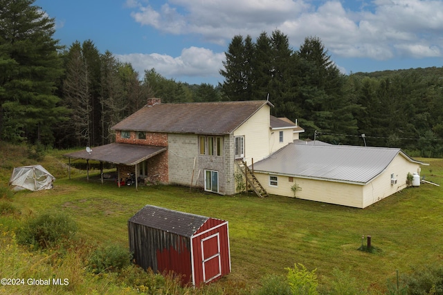 exterior space with a yard, an outdoor structure, a wooded view, and a storage unit