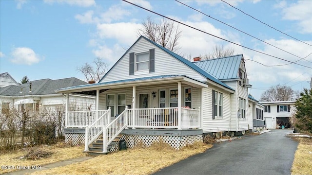 view of front facade with covered porch, a chimney, metal roof, and a standing seam roof