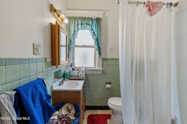 bathroom featuring toilet, a wainscoted wall, vanity, tile walls, and tile patterned floors