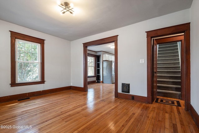 unfurnished room with visible vents, plenty of natural light, stairs, and light wood finished floors