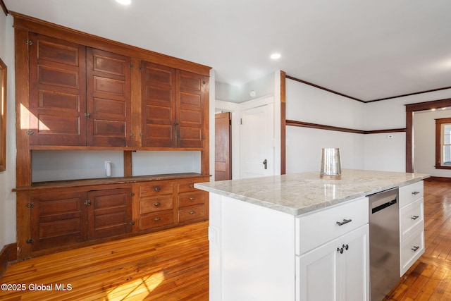 kitchen with light stone countertops, white cabinetry, light wood finished floors, stainless steel dishwasher, and a center island