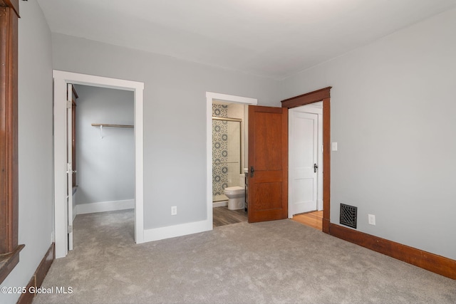 unfurnished bedroom featuring visible vents, a walk in closet, baseboards, carpet flooring, and a closet