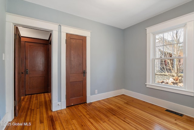 unfurnished bedroom with light wood finished floors, visible vents, and baseboards