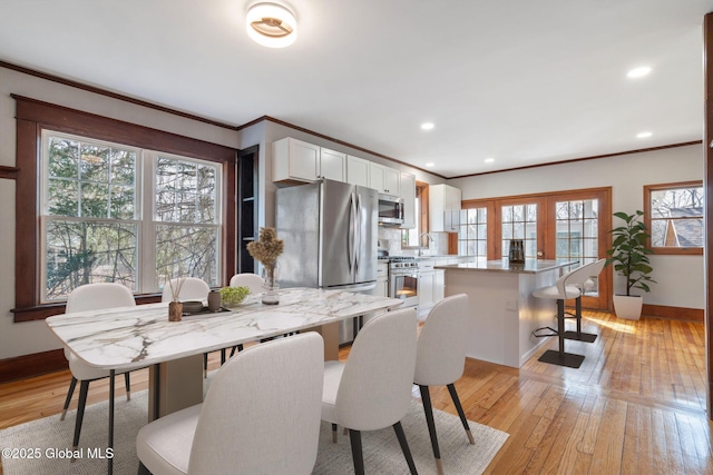 dining area featuring recessed lighting, baseboards, crown molding, and light wood finished floors