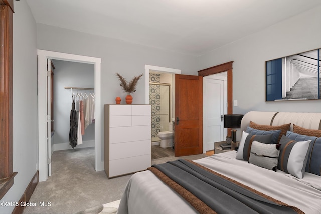 bedroom featuring a spacious closet, connected bathroom, baseboards, light colored carpet, and a closet