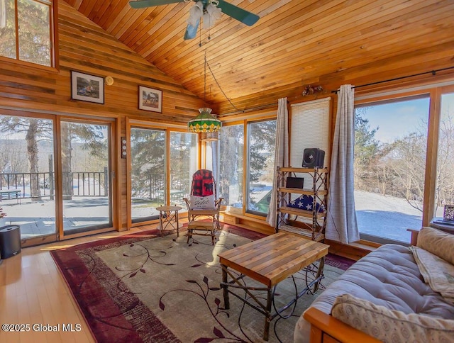 living room with wooden walls, a ceiling fan, wood ceiling, hardwood / wood-style floors, and high vaulted ceiling