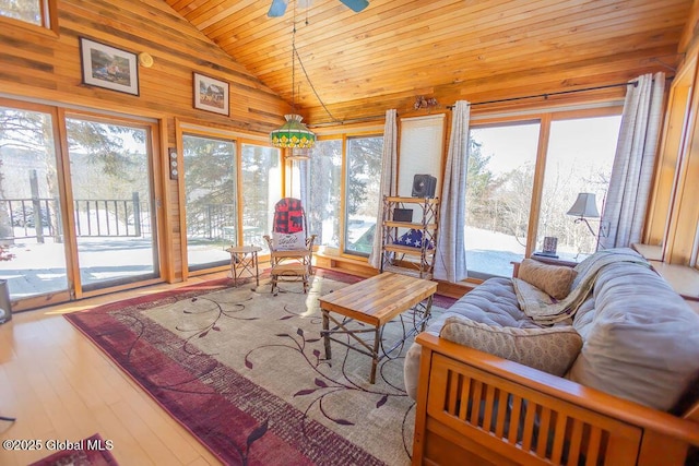 living room with lofted ceiling, a ceiling fan, wood ceiling, wood walls, and wood finished floors