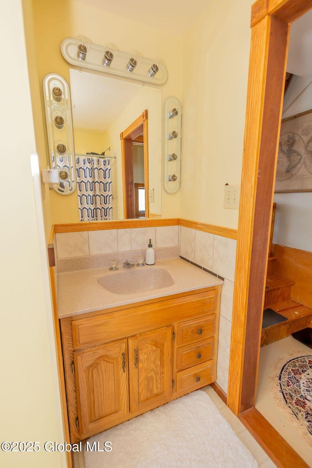 full bathroom featuring wainscoting, tile walls, and vanity