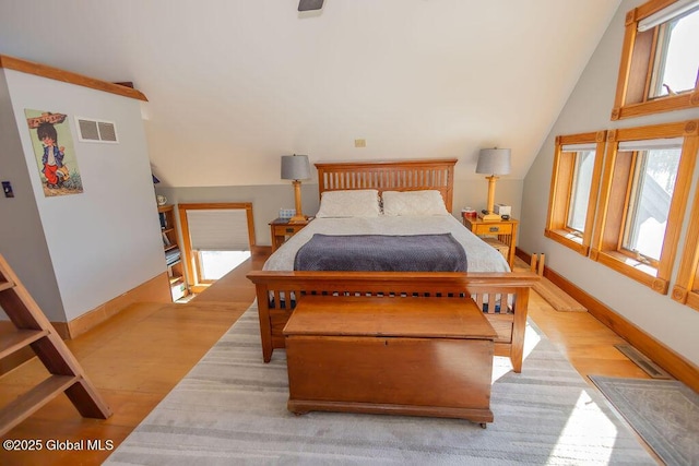 bedroom with vaulted ceiling, wood finished floors, visible vents, and baseboards