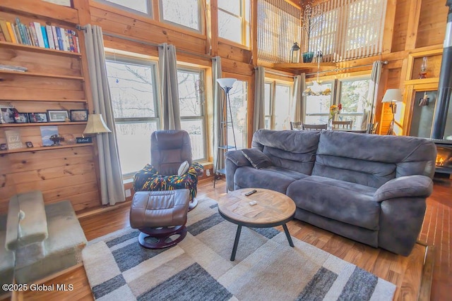 living room featuring a high ceiling, wood finished floors, a wealth of natural light, and wooden walls