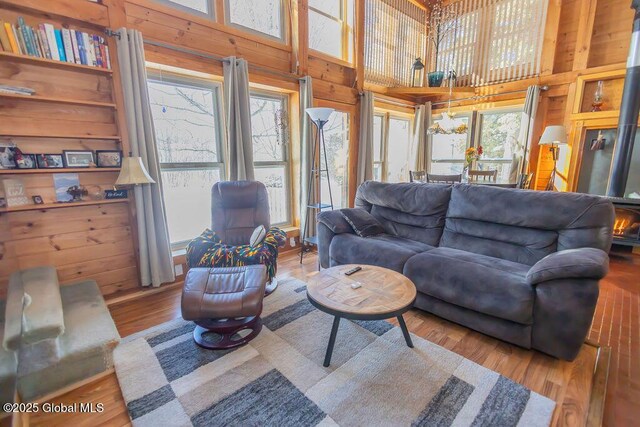 living room featuring a wealth of natural light, wood finished floors, a towering ceiling, and wooden walls