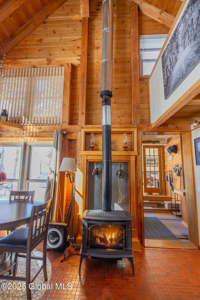 living room with a high ceiling, brick floor, a wood stove, and wooden walls