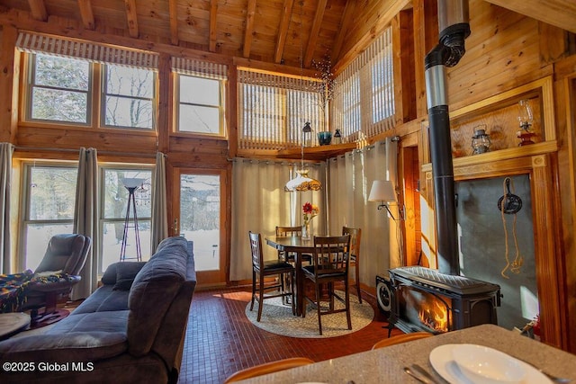 living room with a wealth of natural light, a wood stove, wooden ceiling, and wood walls