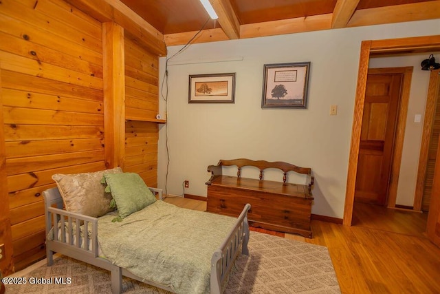 bedroom featuring beam ceiling, baseboards, and wood finished floors