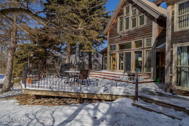 snow covered back of property with a wooden deck