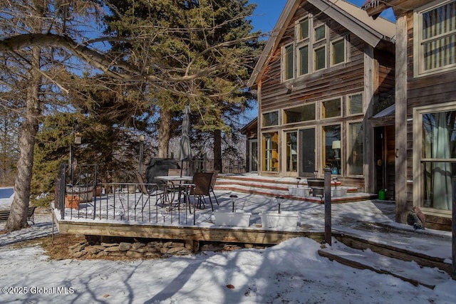 snow covered back of property with a deck