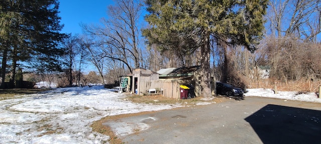 yard covered in snow featuring an outbuilding and a storage unit