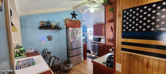 kitchen featuring ceiling fan, light wood-style floors, vaulted ceiling, appliances with stainless steel finishes, and ornamental molding