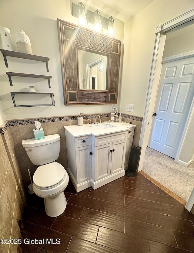 bathroom with toilet, vanity, tile walls, wainscoting, and wood tiled floor