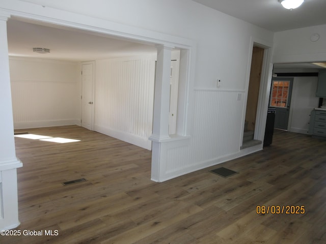 spare room featuring a wainscoted wall, decorative columns, visible vents, and wood finished floors