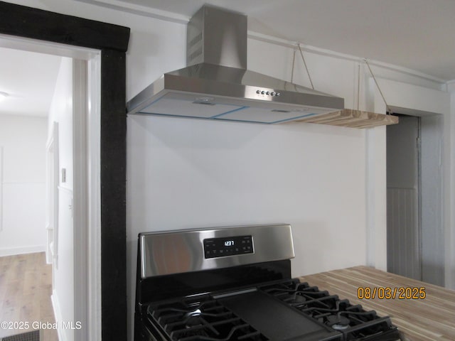 kitchen with wall chimney exhaust hood, stainless steel gas range, and wood finished floors