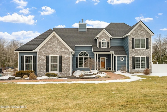 traditional-style home with a chimney, a front yard, and fence