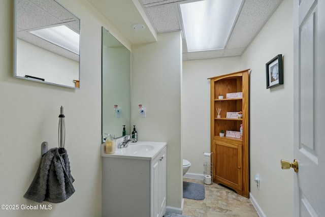 bathroom featuring baseboards, toilet, and vanity