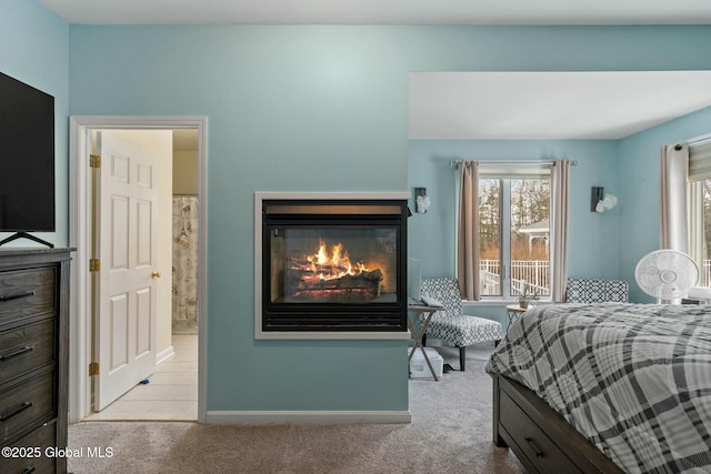 bedroom featuring connected bathroom, multiple windows, a glass covered fireplace, and carpet flooring