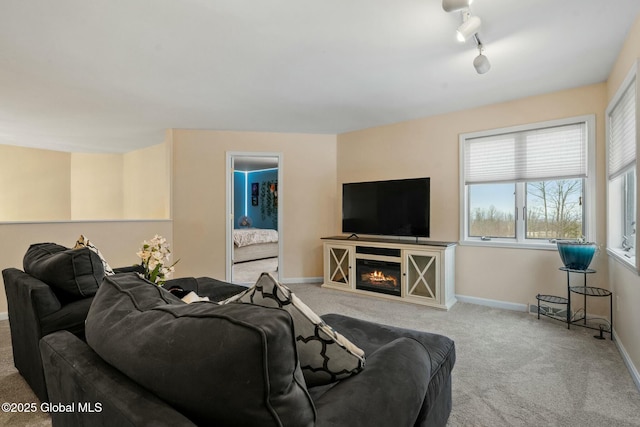 carpeted living room with baseboards, a glass covered fireplace, and track lighting