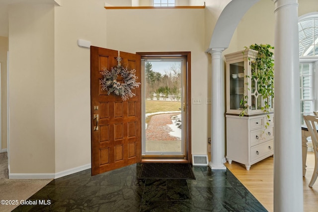 entrance foyer featuring arched walkways, visible vents, baseboards, and ornate columns