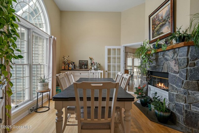 dining room with light wood-type flooring, a fireplace, and french doors