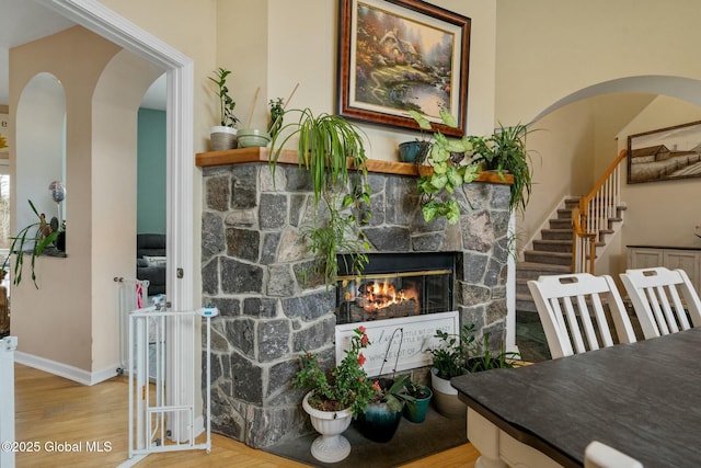 interior space with wood finished floors, stairway, arched walkways, a fireplace, and baseboards