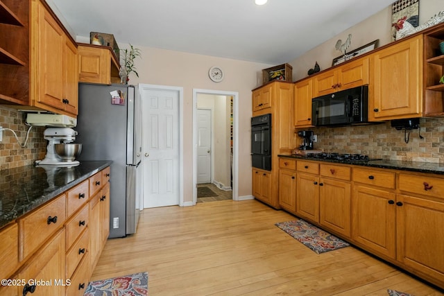 kitchen with black appliances, open shelves, dark stone counters, light wood-style floors, and decorative backsplash