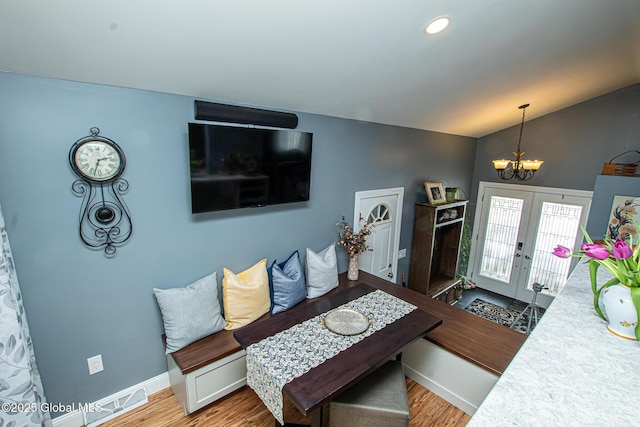 living room featuring french doors, a notable chandelier, vaulted ceiling, wood finished floors, and baseboards