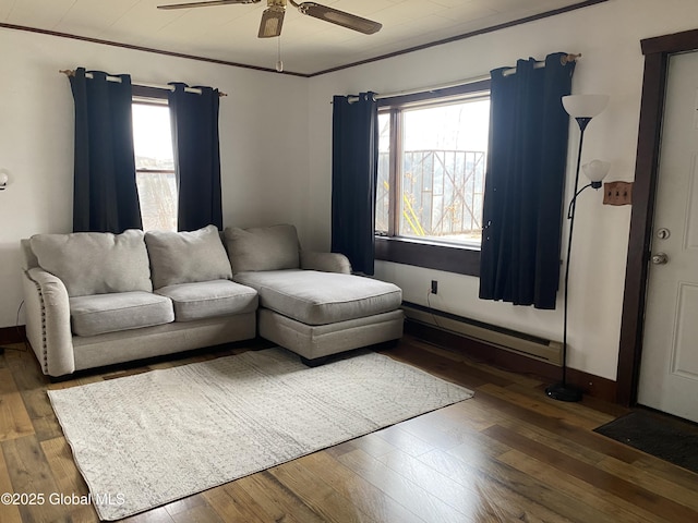 living room featuring a baseboard heating unit, ornamental molding, baseboards, and hardwood / wood-style flooring