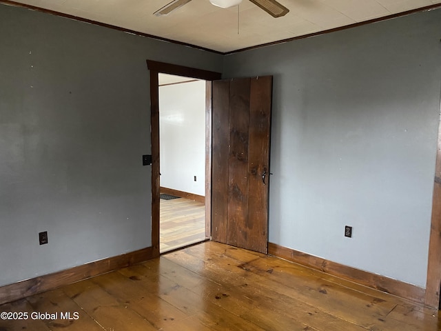 empty room with baseboards, a ceiling fan, hardwood / wood-style flooring, and crown molding