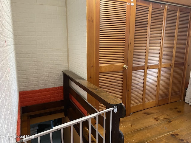 stairway with brick wall and wood-type flooring