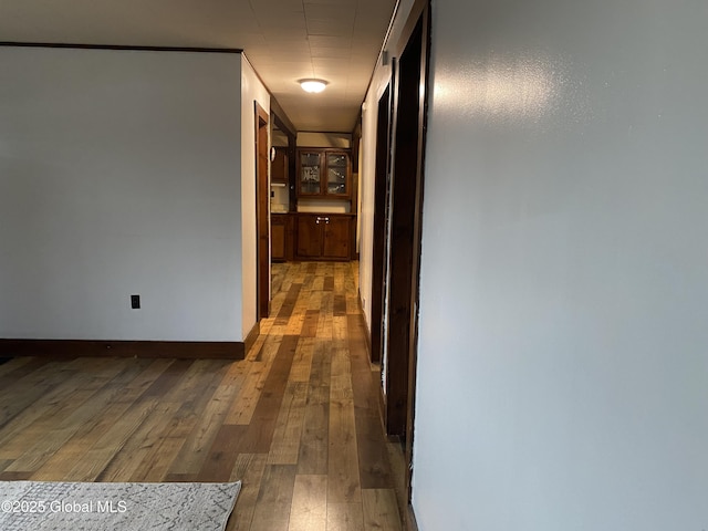 hallway featuring hardwood / wood-style flooring and baseboards