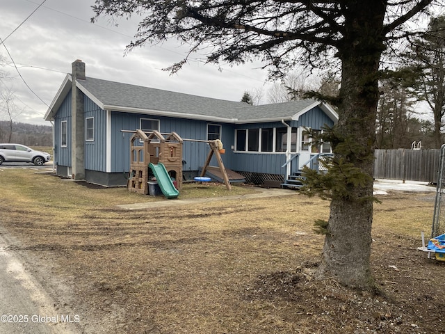 view of front of house with roof with shingles, a chimney, and fence