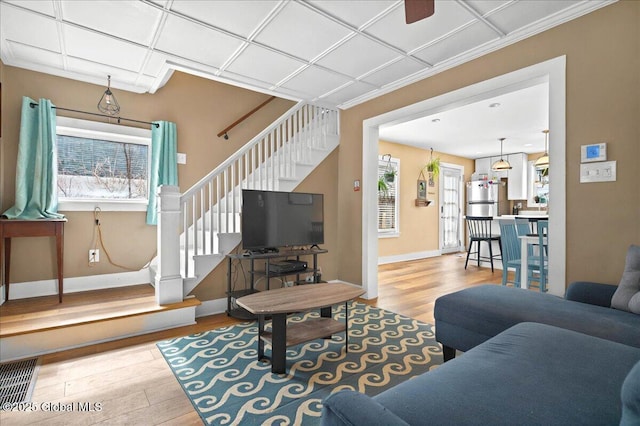 living area with baseboards, stairway, and wood finished floors