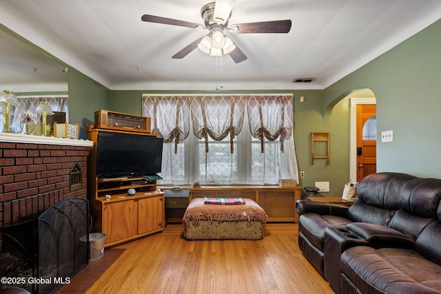 living room with a ceiling fan, visible vents, arched walkways, and wood finished floors