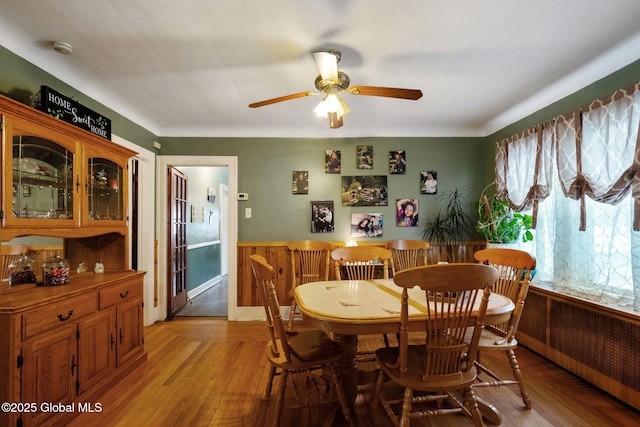 dining area with a ceiling fan, light wood-type flooring, and radiator heating unit