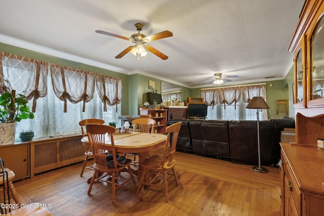 dining area featuring ceiling fan, radiator heating unit, and wood finished floors