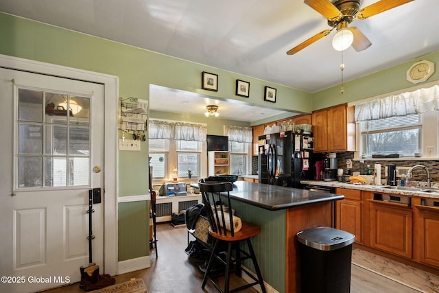 kitchen with a breakfast bar area, backsplash, freestanding refrigerator, a kitchen island, and a sink