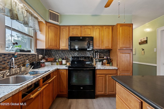 kitchen featuring visible vents, a sink, light wood-type flooring, black appliances, and backsplash